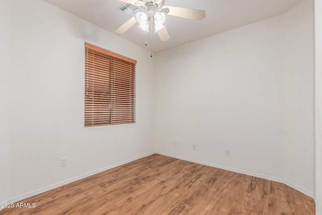 spare room featuring light wood-type flooring, a ceiling fan, and baseboards