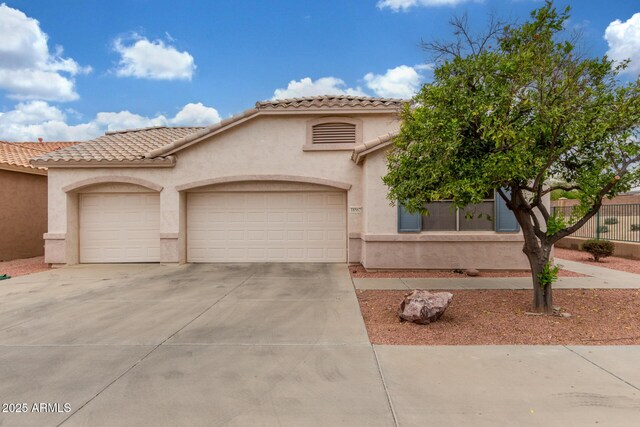 mediterranean / spanish home featuring stucco siding, an attached garage, concrete driveway, and a tiled roof