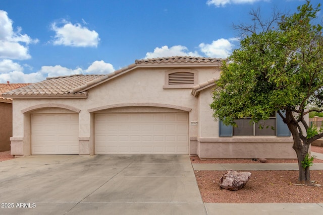 mediterranean / spanish home featuring stucco siding, a tile roof, an attached garage, and concrete driveway