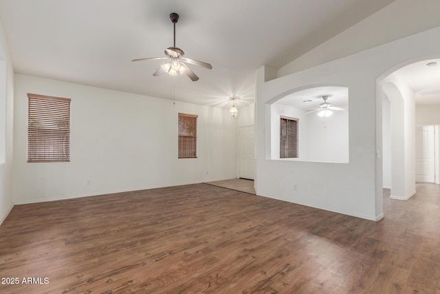 empty room with arched walkways, vaulted ceiling, a ceiling fan, and wood finished floors