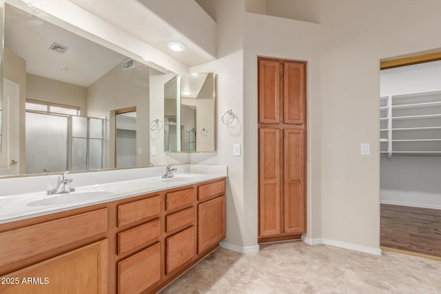 full bathroom featuring a walk in closet, visible vents, a sink, and double vanity