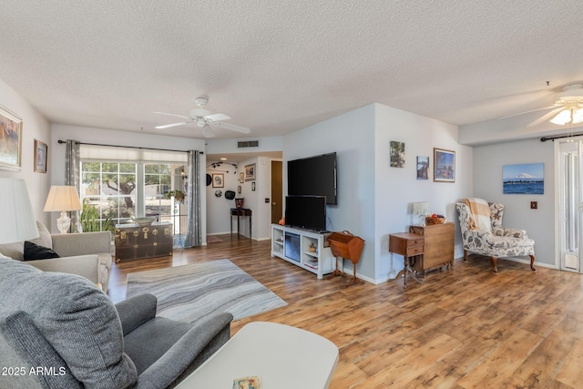 living area with light wood-style flooring, a textured ceiling, and ceiling fan