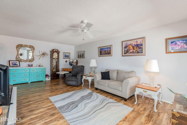 living room with wood finished floors, a textured ceiling, and a ceiling fan
