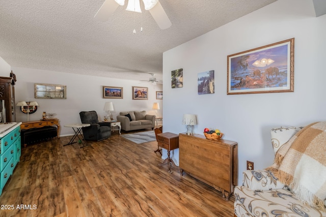 living room featuring ceiling fan, wood finished floors, and a textured ceiling