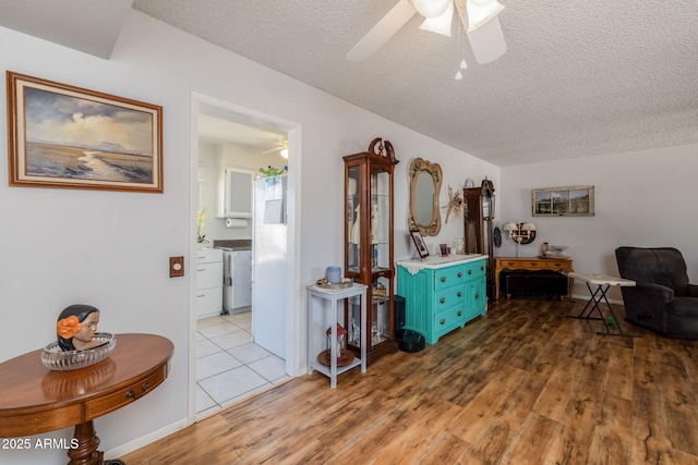 sitting room with washer / dryer, wood finished floors, a textured ceiling, and ceiling fan