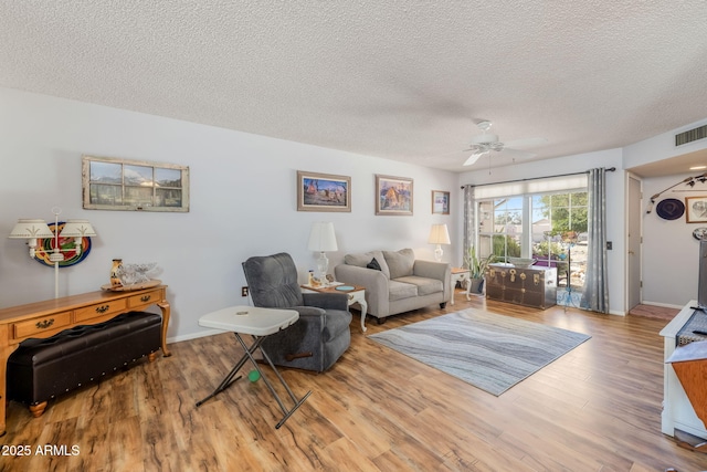 living room featuring a ceiling fan, wood finished floors, a textured ceiling, and visible vents