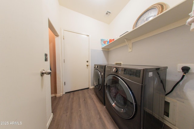 laundry room with visible vents, baseboards, laundry area, wood finished floors, and washer and clothes dryer