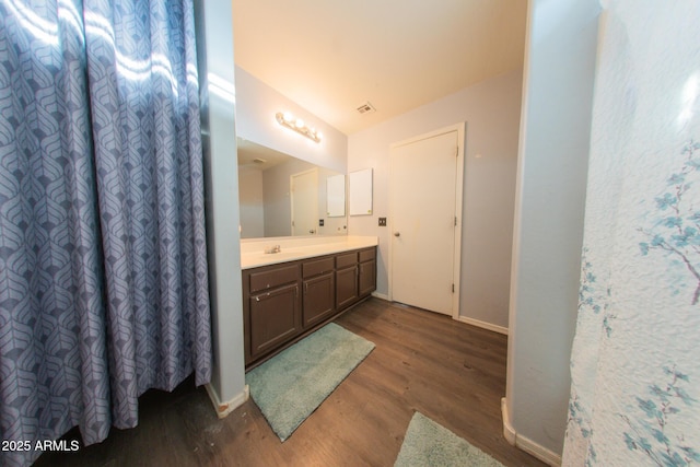 full bath featuring wood finished floors, vanity, baseboards, and visible vents