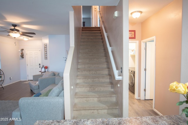 staircase with washer / clothes dryer, ceiling fan, wood finished floors, and baseboards