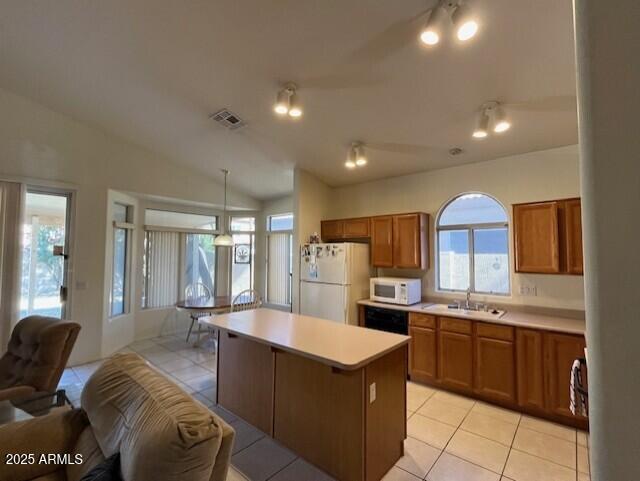 kitchen featuring pendant lighting, white appliances, a kitchen island, vaulted ceiling, and light tile patterned floors