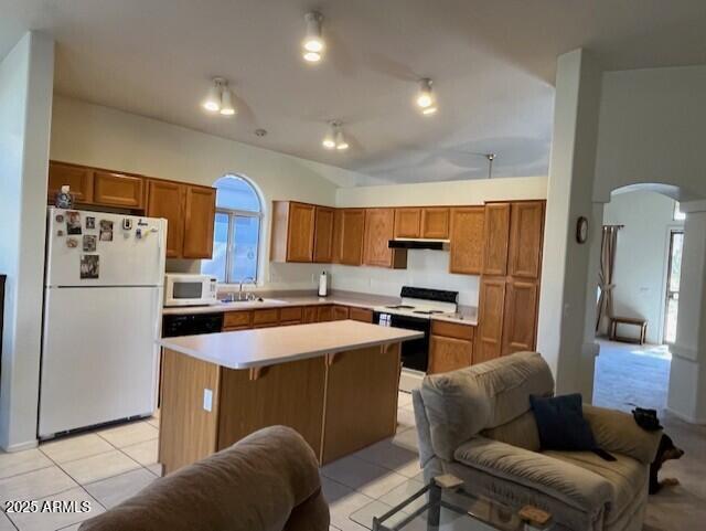 kitchen with a center island, sink, white appliances, a kitchen breakfast bar, and light tile patterned floors