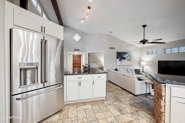 kitchen featuring white cabinetry, lofted ceiling, high quality fridge, and dark stone countertops