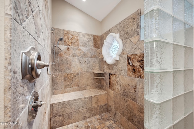 bathroom featuring lofted ceiling and a tile shower