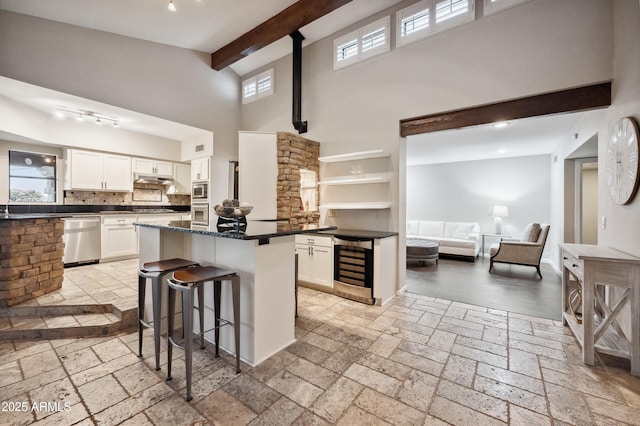 kitchen with dishwasher, white cabinets, a kitchen breakfast bar, beverage cooler, and a center island