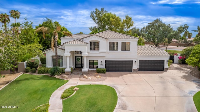 mediterranean / spanish home with driveway, stucco siding, a tile roof, fence, and a front yard