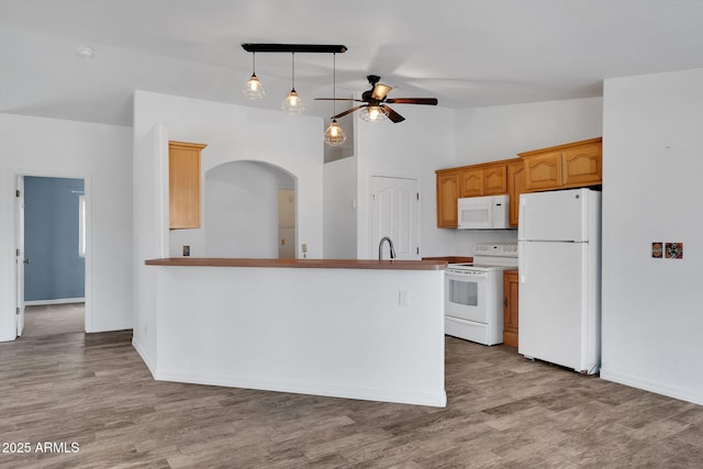 kitchen with white appliances, ceiling fan, hardwood / wood-style floors, hanging light fixtures, and vaulted ceiling