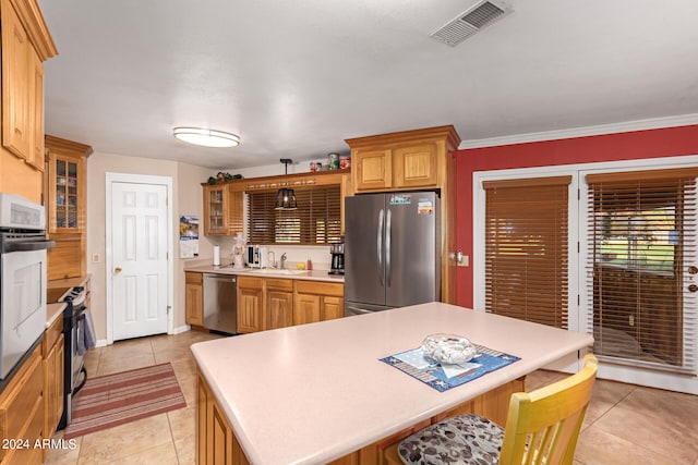 kitchen with crown molding, a kitchen breakfast bar, sink, appliances with stainless steel finishes, and light tile patterned floors