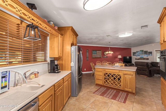 kitchen with decorative light fixtures, sink, stainless steel appliances, ornamental molding, and light tile patterned floors