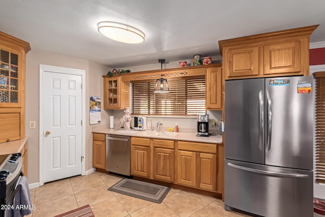 kitchen with stainless steel appliances, sink, hanging light fixtures, light tile patterned floors, and a textured ceiling