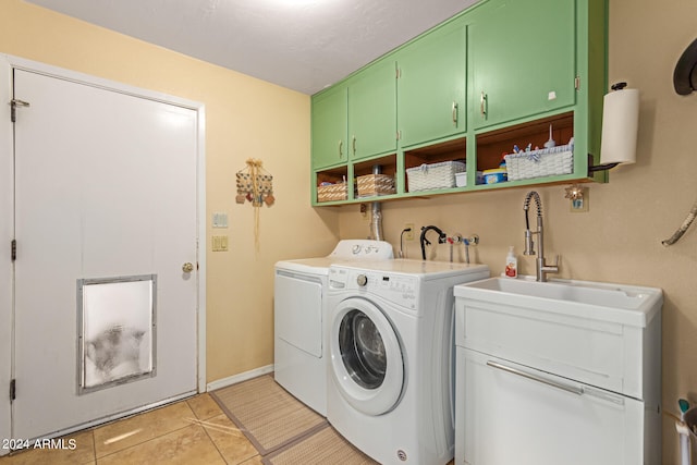 laundry room with washing machine and clothes dryer, cabinets, and light tile patterned floors