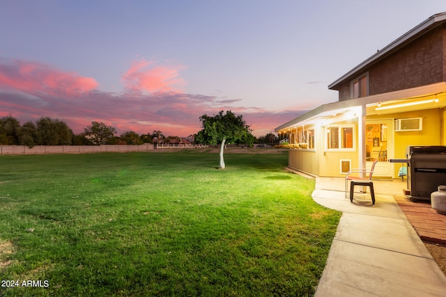 yard at dusk featuring a wall mounted air conditioner and a patio area