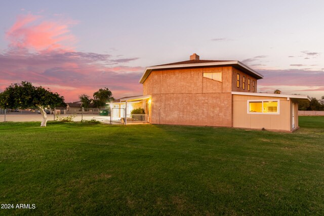 back house at dusk featuring a yard