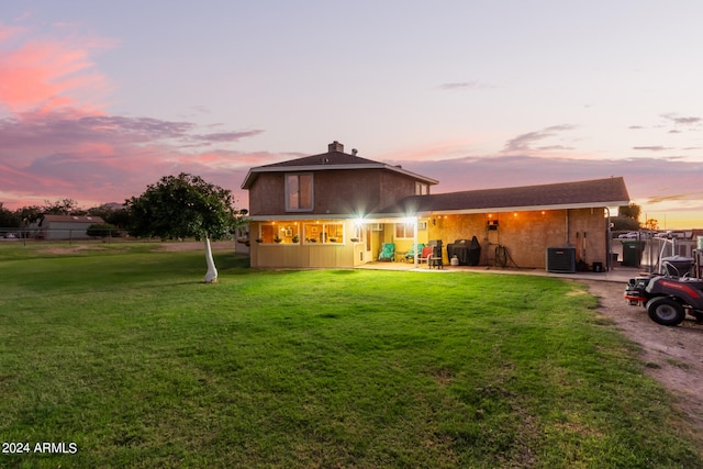 view of front of property featuring a yard, a patio area, and central AC unit