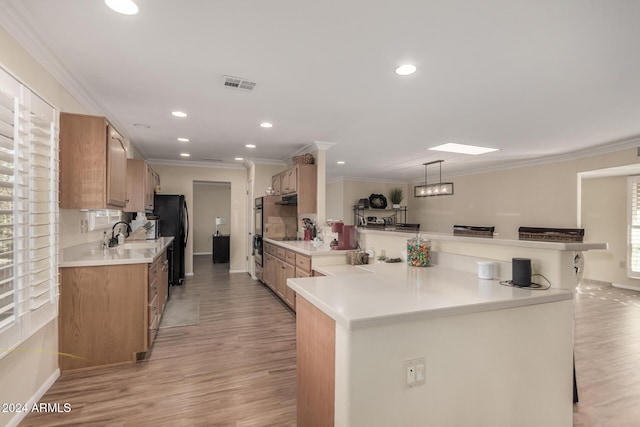 kitchen featuring a kitchen breakfast bar, sink, crown molding, light hardwood / wood-style flooring, and kitchen peninsula