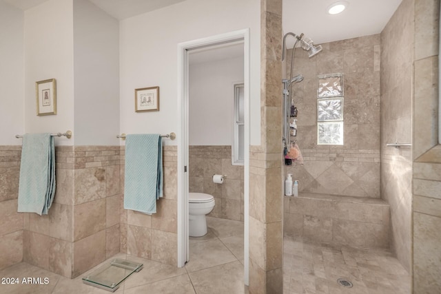 bathroom featuring a tile shower, toilet, tile walls, and tile patterned floors