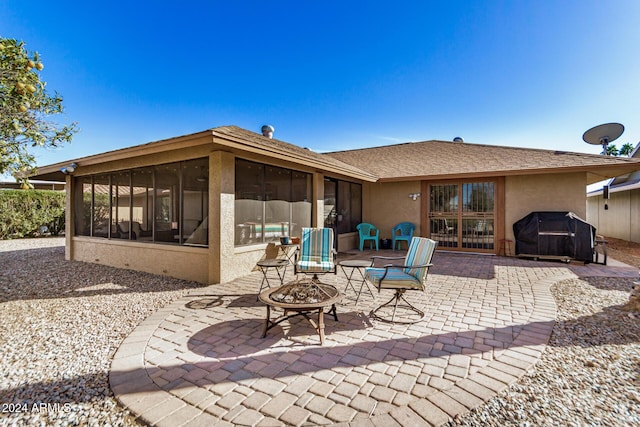 rear view of house with a patio area, a sunroom, and a fire pit