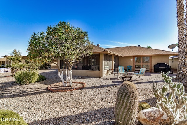 back of house with a sunroom, a patio, and a fire pit