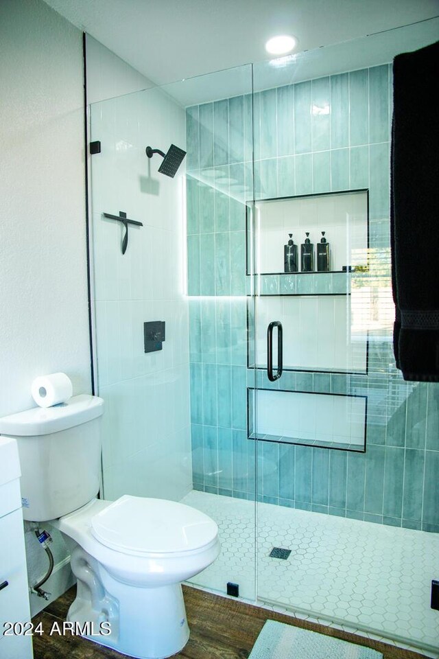 bathroom featuring a shower with door, vanity, hardwood / wood-style floors, and toilet