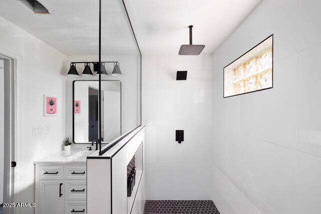 bathroom with tiled shower and vanity