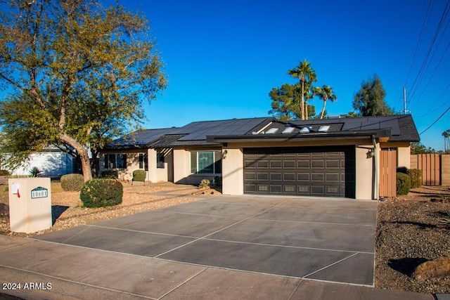 single story home with a garage and solar panels