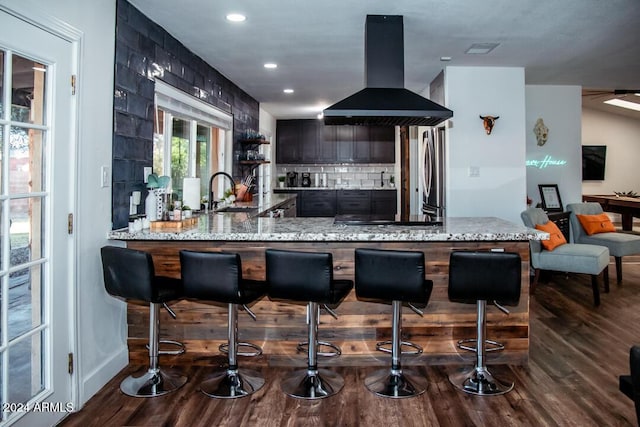 kitchen featuring dark wood-type flooring, sink, wall chimney exhaust hood, appliances with stainless steel finishes, and kitchen peninsula