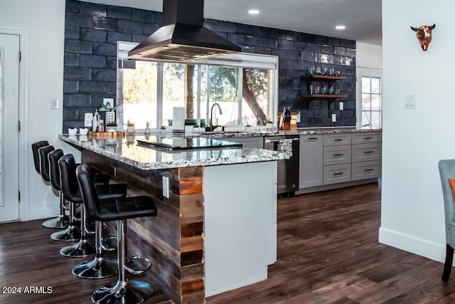 bar featuring light stone countertops, sink, dark wood-type flooring, stainless steel dishwasher, and island range hood