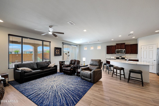 living room featuring ceiling fan, sink, and light hardwood / wood-style floors