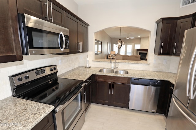 7021 E Earll Dr Unit 204, Scottsdale, AZ 85251 - kitchen featuring stainless steel appliances, a sink, arched walkways, dark brown cabinetry, and backsplash