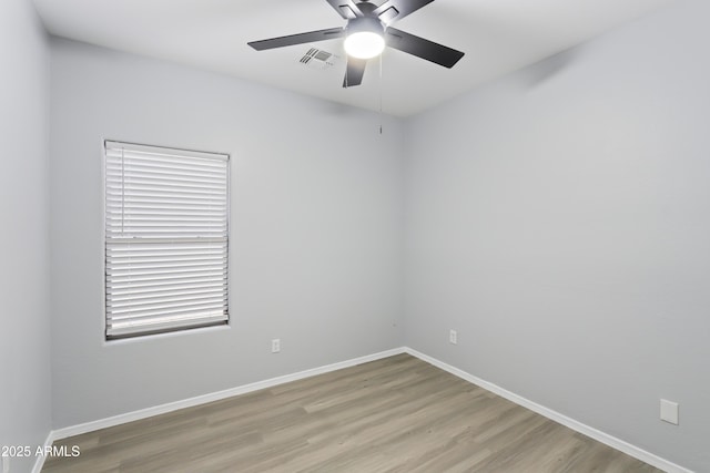 spare room featuring visible vents, baseboards, ceiling fan, and wood finished floors