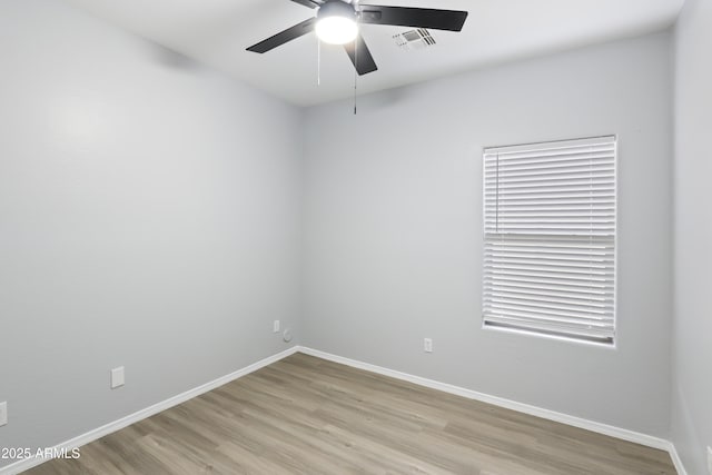 spare room with baseboards, light wood-style flooring, ceiling fan, and visible vents