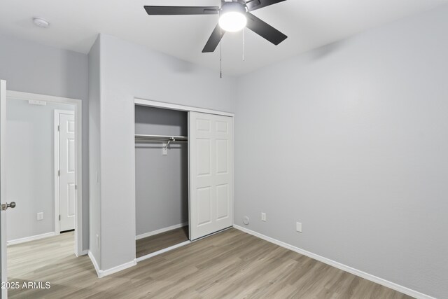 unfurnished bedroom with a ceiling fan, light wood-style flooring, a closet, and baseboards