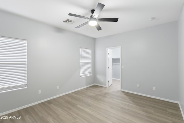 unfurnished room featuring a ceiling fan, baseboards, light wood finished floors, and visible vents