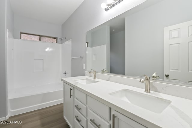 bathroom featuring double vanity, a sink,  shower combination, and wood finished floors
