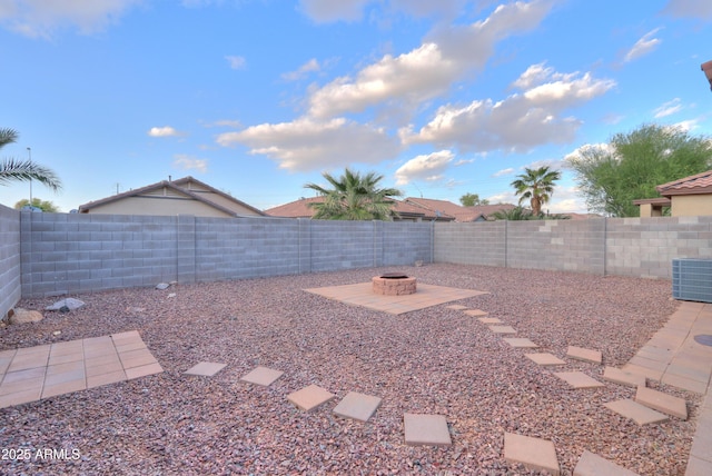 view of yard featuring a patio, a fire pit, central AC, and a fenced backyard