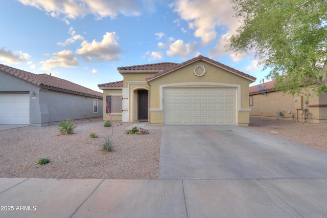 mediterranean / spanish-style home with stucco siding, driveway, a garage, and a tiled roof