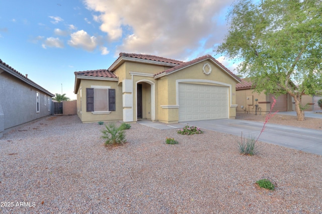 mediterranean / spanish house with stucco siding, fence, a tiled roof, driveway, and a garage