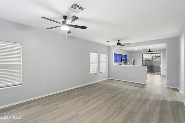 unfurnished living room with baseboards, light wood-style floors, ceiling fan, and visible vents