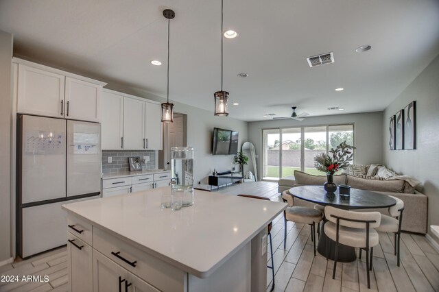 kitchen featuring backsplash, hanging light fixtures, high end white refrigerator, a center island, and white cabinets