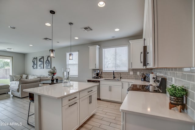 kitchen with a kitchen island, white cabinets, range, backsplash, and pendant lighting