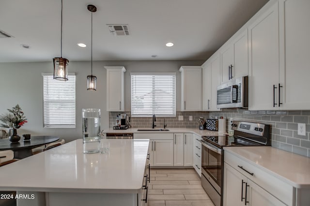 kitchen featuring stainless steel appliances, sink, a center island, and pendant lighting